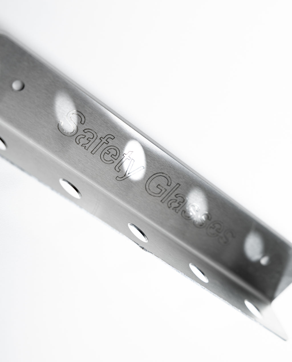 Metal safety glass bracket with 'Safety Glass' branding. Metal corner bracket with 'Safety Glasses' engraving. The TLC Glasses Holder 5 Slot keeps safety glasses organized, visible, and accessible in Lean workplaces. Ideal for factories, warehouses, workshops, and production areas, it minimizes loss, damage, and clutter. With five slots, it supports shared use and proper PPE storage, reinforcing safety habits and aligning with 5S and 6S standards. A simple solution for improving PPE organization and workpla