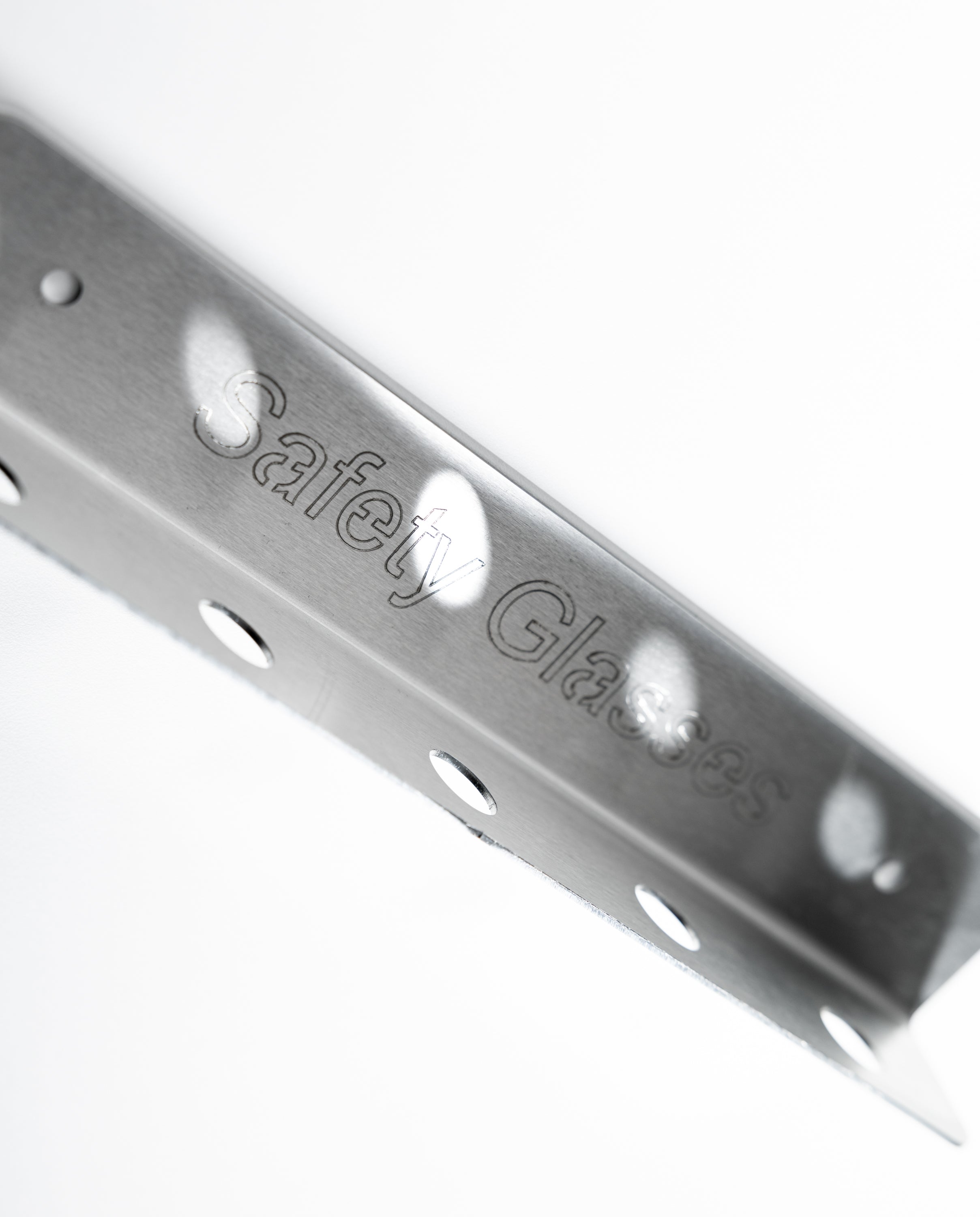 Metal safety glass bracket with 'Safety Glass' branding. Metal corner bracket with 'Safety Glasses' engraving. The TLC Glasses Holder 5 Slot keeps safety glasses organized, visible, and accessible in Lean workplaces. Ideal for factories, warehouses, workshops, and production areas, it minimizes loss, damage, and clutter. With five slots, it supports shared use and proper PPE storage, reinforcing safety habits and aligning with 5S and 6S standards. A simple solution for improving PPE organization and workpla